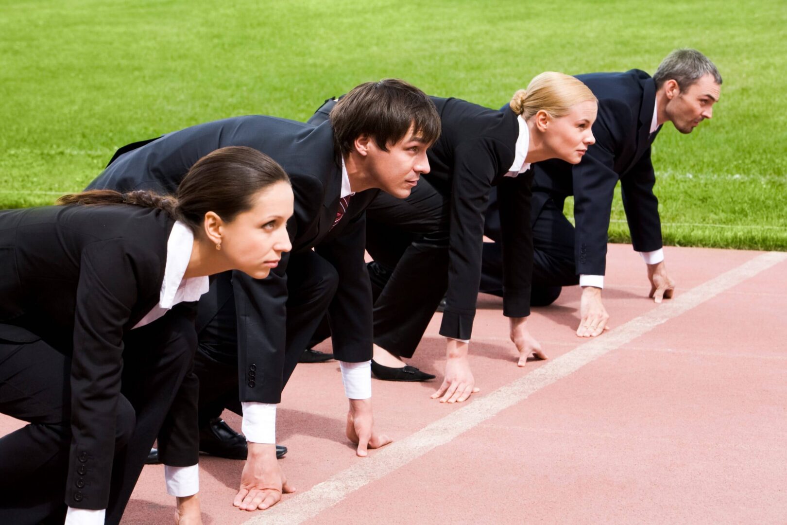 Colleagues in suits crouched on running lane