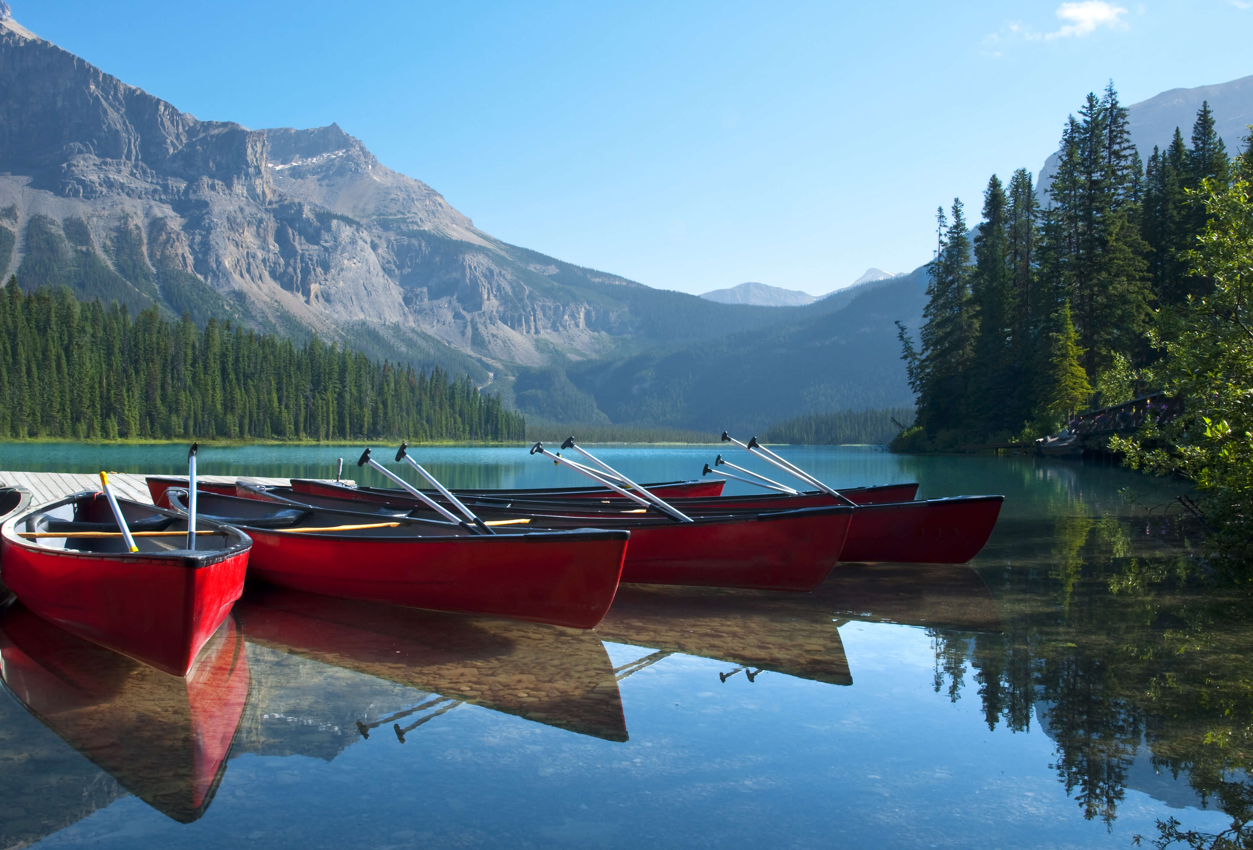 Docked red canoes reflecting on turquoise water