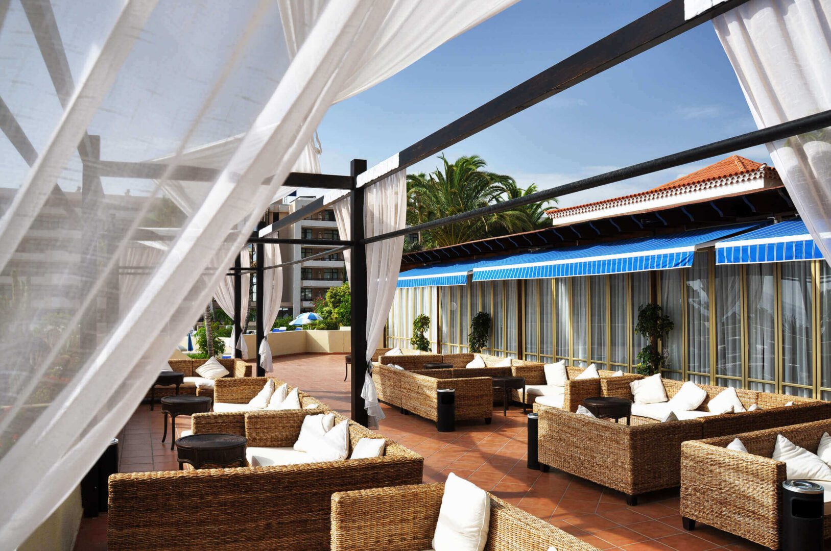 Outdoor patio with wicker furniture and drapes.